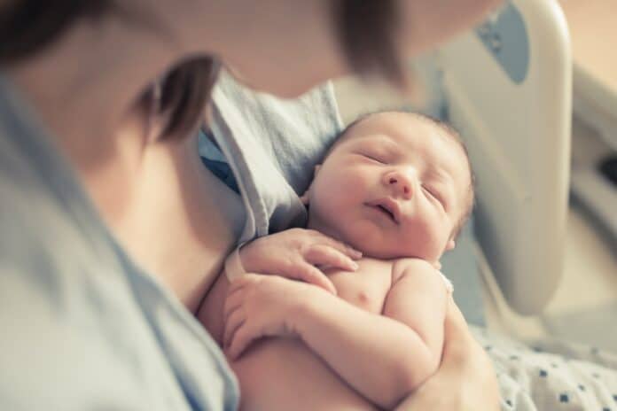 Parenting and new life concept. Mother holding newborn baby boy in her arms. bonus