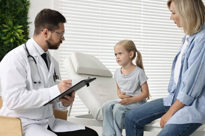 Doctor consulting little girl with stomach pain and her mother in hospital microbioma antibiotici