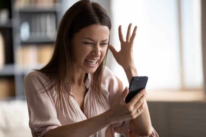 Mad female having problems working on modern cellphone telemarketing
