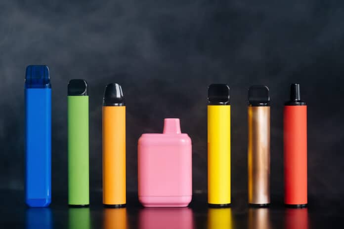 ECIG USA E GETTA A set of colorful disposable electronic cigarettes of different shapes on a black background with smoke. Concept of modern smoking, vaping and nicotine. ECIG USA E GETTA