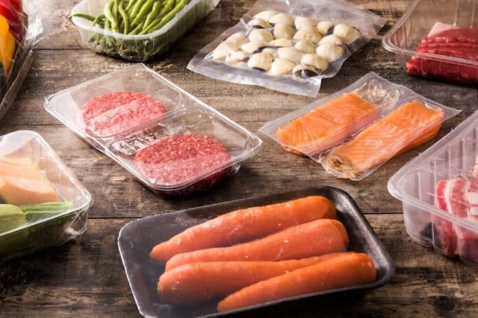 different types of packaged food. Meat, green beans, carrots and salmon on wooden table PLASTIFICANTI