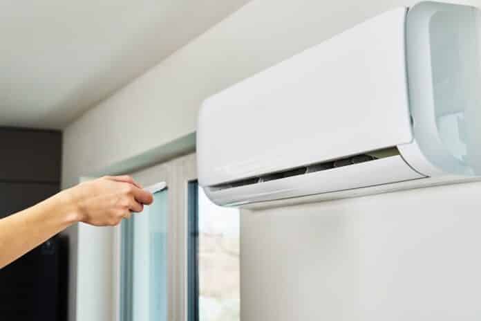 Hand adjusting temperature on air conditioner condizionatori