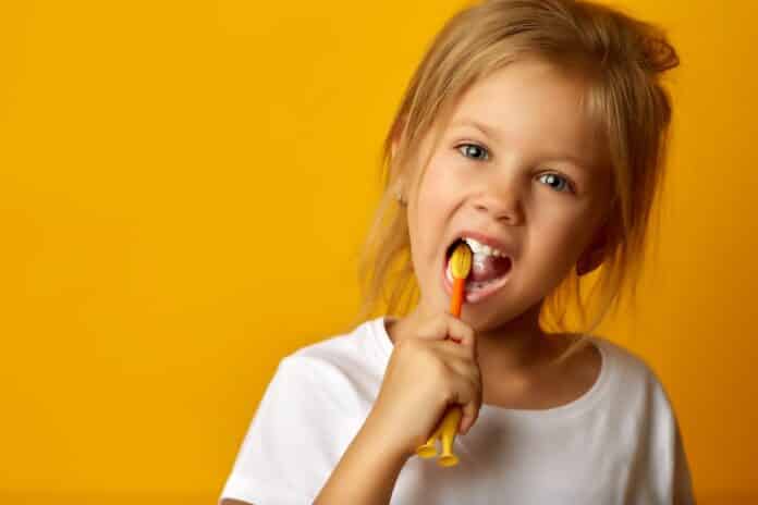 Adorable girl brushing teeth with kids toothbrush