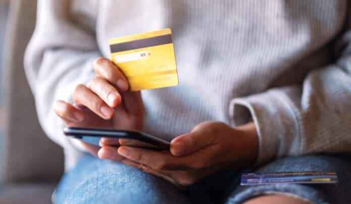 Closeup image of a woman using credit card for purchasing and shopping online on mobile phone CARTA DI CREDITO