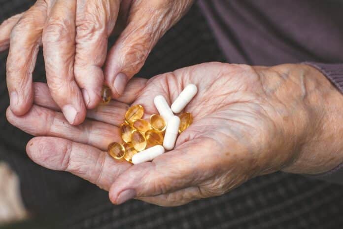 Close-up of elderly woman's hands holding capsules and pills, showing daily vitamins and supplements, concept of health and aging. FARMACI ANZIANI