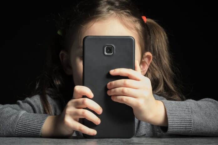 Problem of kids addiction to gadgets, online and screen time. Little girl with big smartphone in her hands ADHD