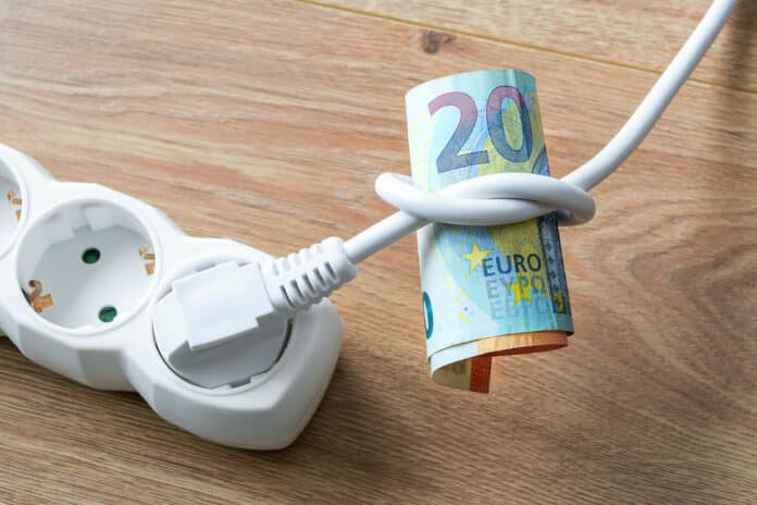 EZWATT PRO BOLLETTE White electric cable with plug tied to a knot on a roll of euro banknotes. Cost of electricity and expensive energy concepts. On a wood surface. EZWATT PRO BOLLETTE