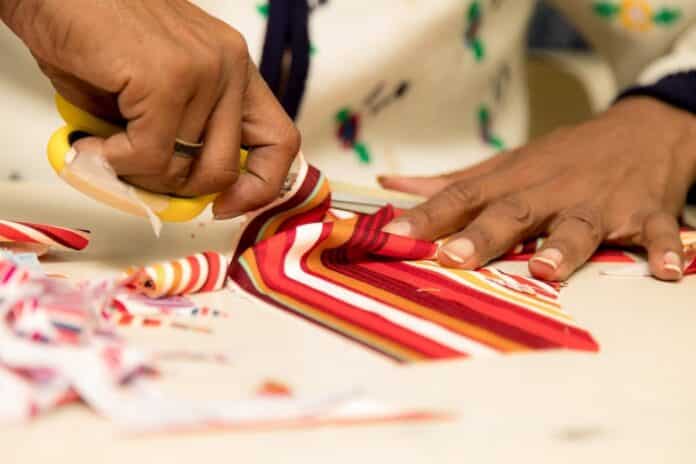 Mãos de trabalhadores da indústria têxtil manuseando tecidos. São Paulo, Brasil. caporalato tessile