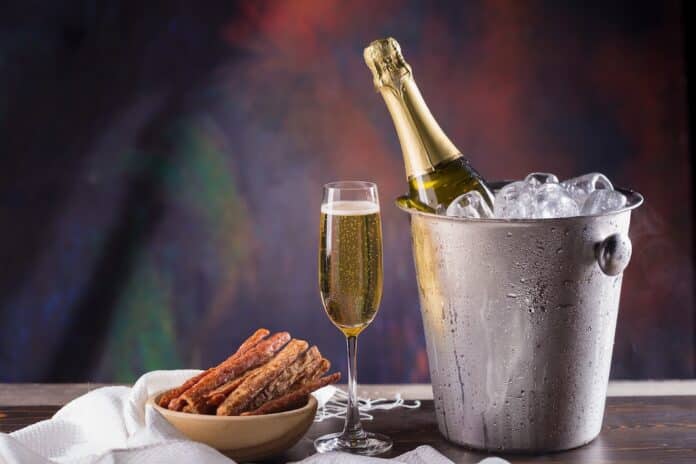 Champagne bottle in bucket with ice and glasses of champagne on dark background CHAMPAGNE