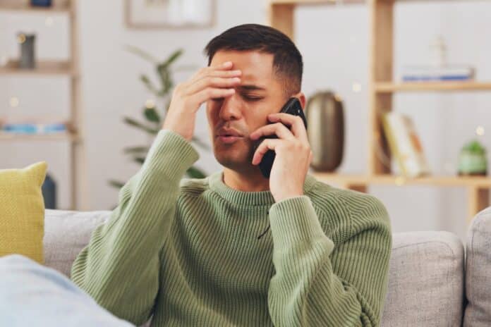 Angry, man and phone call communication in home with anger problem, stress and conflict on sofa lounge. Frustrated male person, smartphone and talking for mobile conversation, argument and complaint MARKETING SELVAGGIO TELEFONATE TRUFFA