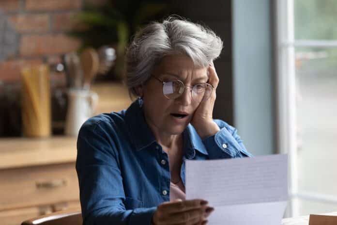 Unhappy senior woman shocked by bad news in postal correspondence BOLLETTE TELERISCALDAMENTO