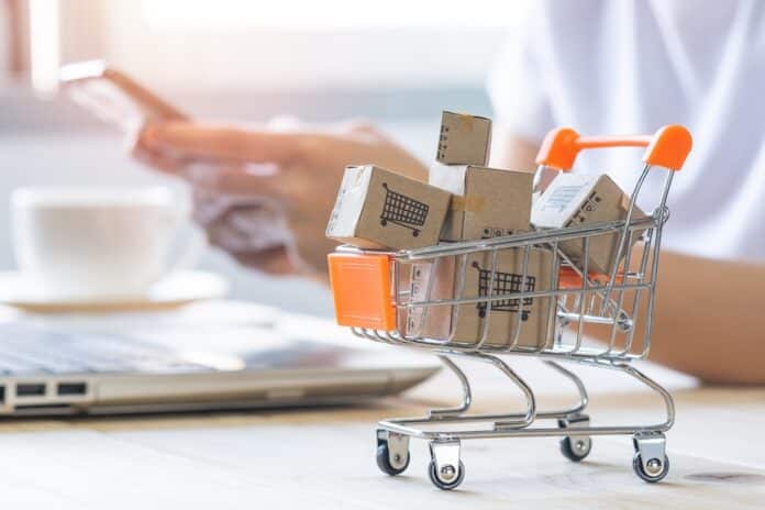 Shopping cart with Paper box or parcel with blur background woman holding mobile phone. Businesswoman or entrepreneur working from home. Online shopping, e-commerce,internet banking, spending money. supermercati spesa