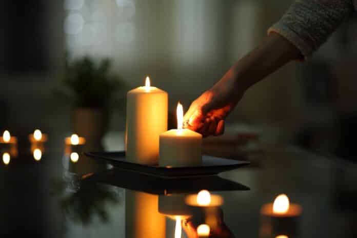 Close up of woman hand lighting candle in the night CANDELE