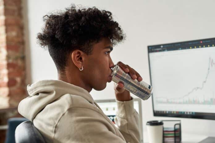 Portrait focused african american trader drinking energy drink near screens with data index chart stock market CAFFEINA