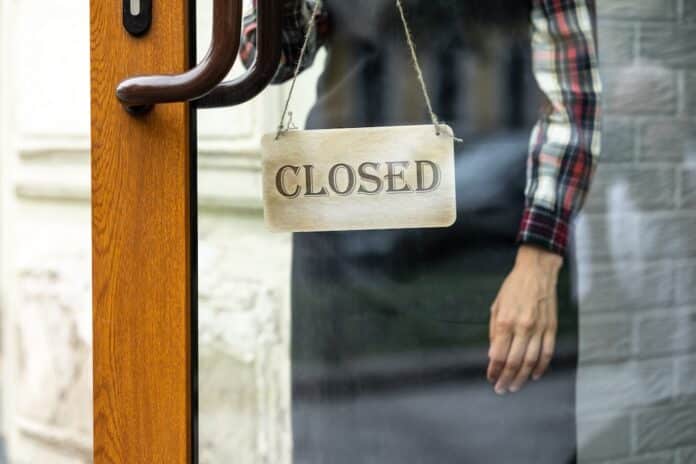 woman holds a sign with the inscription open or closed at the door of a restaurant or coffee shop. the working hours of the restaurant SUPERMERCATI APERTI LA DOMENICA