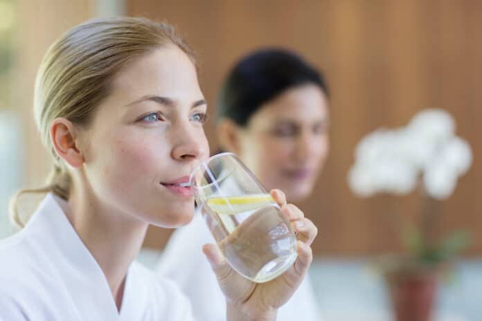 BICCHIERE ACQUA LIMONE Beautiful young woman drinking lemon water in spa BICCHIERE ACQUA LIMONE