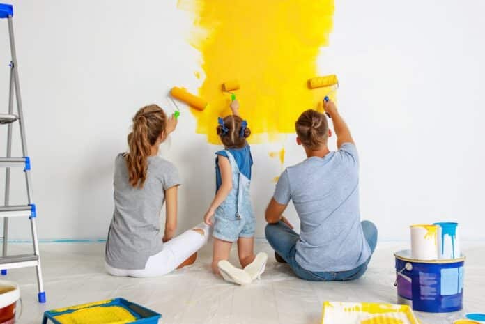 Repair in apartment. Happy family mother, father and child daughter paints wall VERNICI