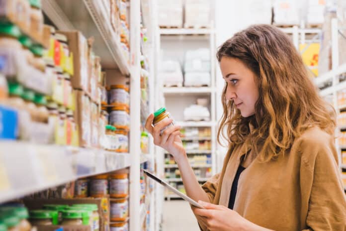 HIPP VELENO TOPI Young beautiful woman with a tablet picks baby food in a supermarket, the girl is studying the composition of the product close-up HIPP VELENO TOPI