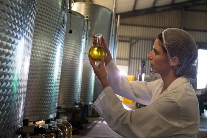 Female technician examining olive oil EXTRAVERGINE OLIO