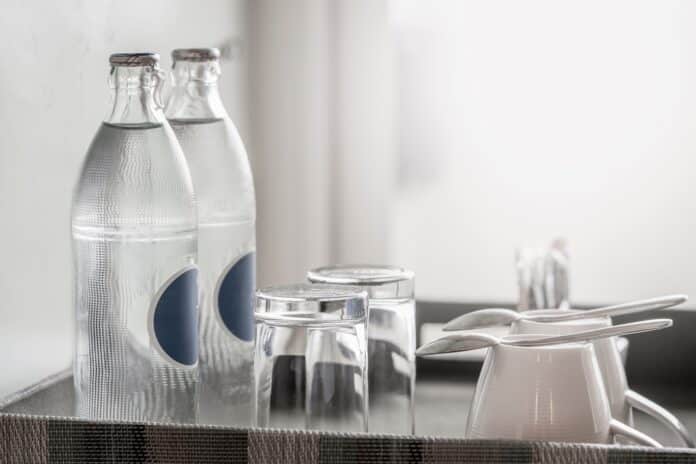 two bottles of mineral water in the hotel room, as well as clean glasses on a tray acqua