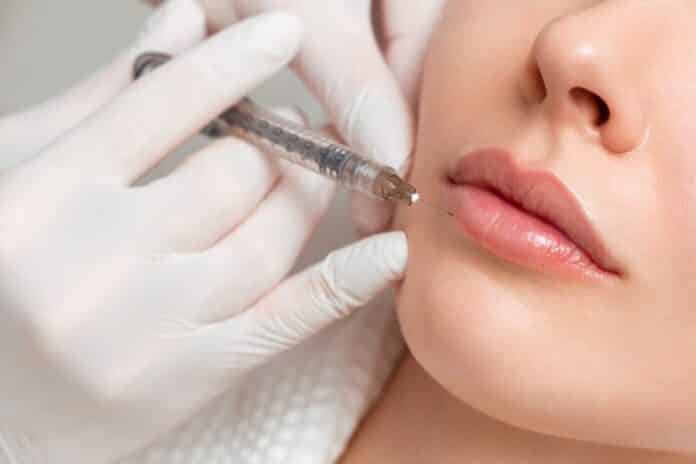 A woman makes lip shape correction in a cosmetology clinic. Lips injections, lip augmentation. filler