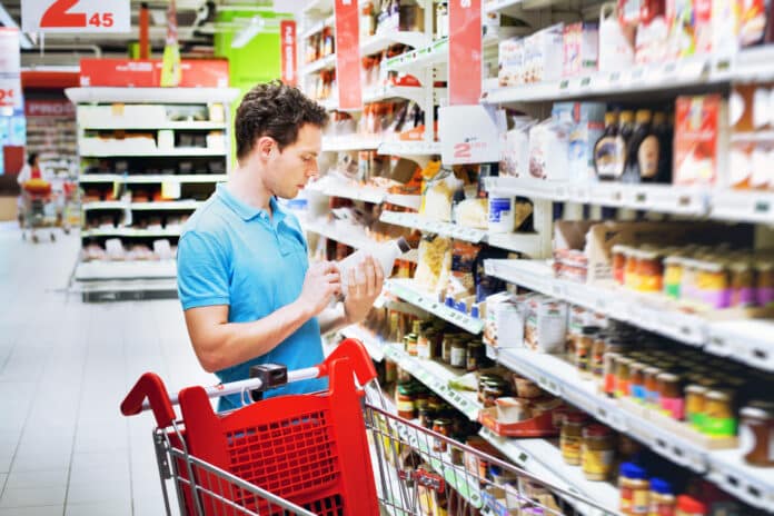 man reading label on the bottle in supermarket etichetta