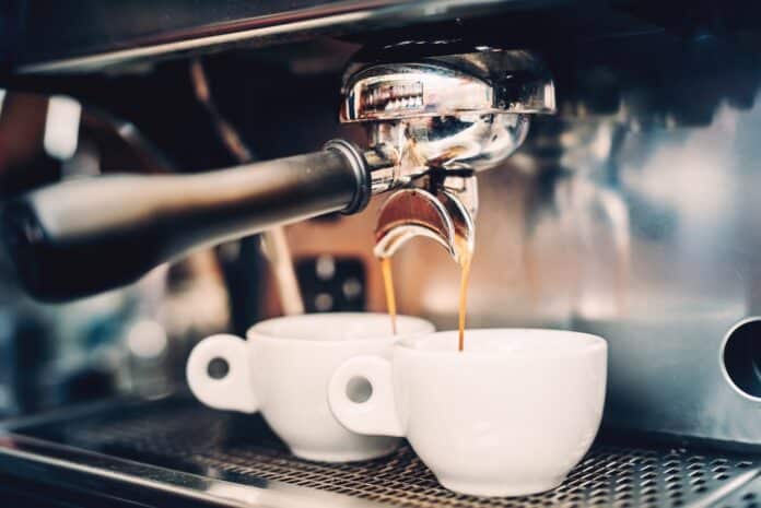 Proffessional brewing - coffee bar details. Espresso coffee pouring from espresso machine. Barista details in cafe CAFFÈ
