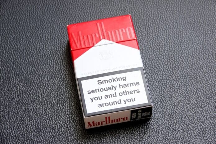 Un paquet de cigarettes usagé de la marque Marlboro posé sur une surface noire I AM MARLBORO