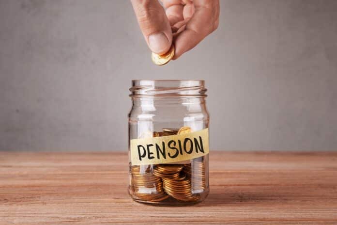 5055465 Pension. Glass jar with coins and an inscription pension. Man holds coin in his hand tfr