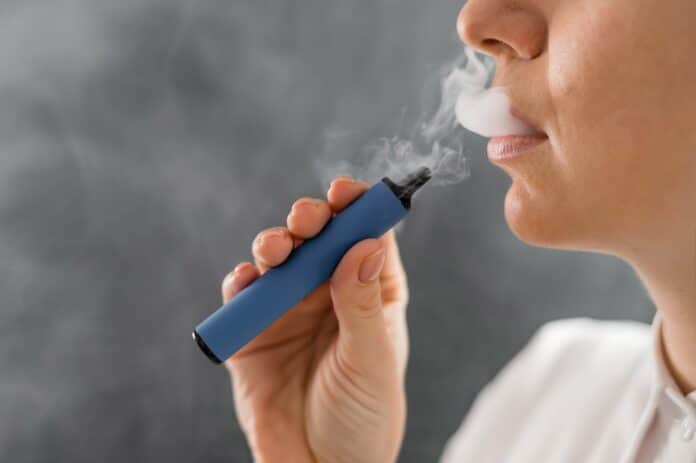Caucasian woman smokes a disposable vape in the studio. e-cig
