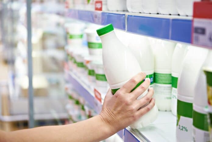 Woman chooses milk and dairy products at store latte