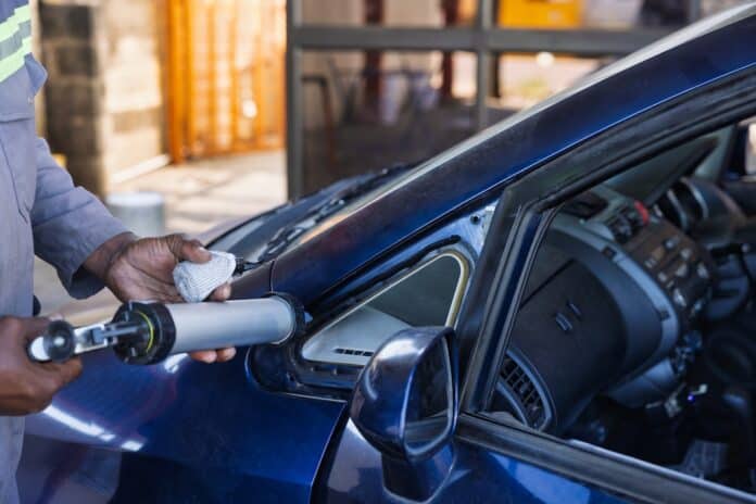 African Worker Repairing Car Window Frame with Sealant Gun replacement glass repair process ricambi auto