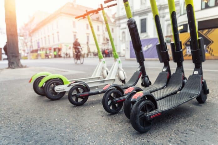 Many modern electric kick scooters sharing parked on city street. Self-service stree transport rental service. Rent urban mobility vehicle with smartphone application. Zero emission green eco energy. monopattini