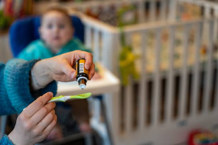 Baby vitamin D supplementation with liquid drops on spoon given by parent INTEGRATORI VITAMINA D NEONATI