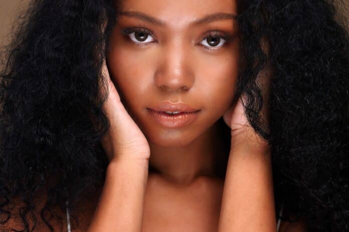 Portrait of a black girl with curly hair, soft makeup and perfect skin. Beautiful face of young black woman with natural skin. LISCIANTI CAPELLI