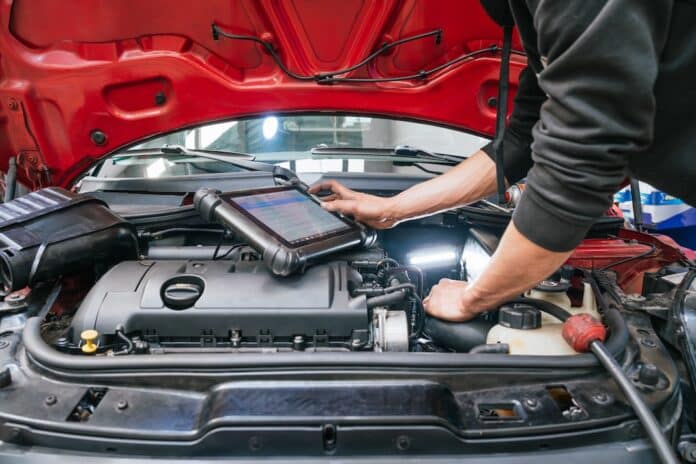 Mechanic diagnosing car engine problems using digital tablet in auto repair shop codice strada