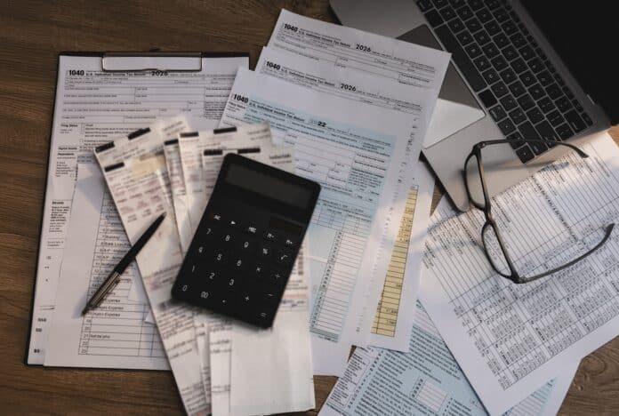 Tax forms, receipts, and calculator arranged on a desk with financial documents and laptop, supporting tax preparation, accounting review, expense calculation, and tax filing workflow. cartelle multe