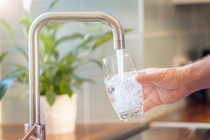 Filling up a glass with drinking water from kitchen tap acqua pfas